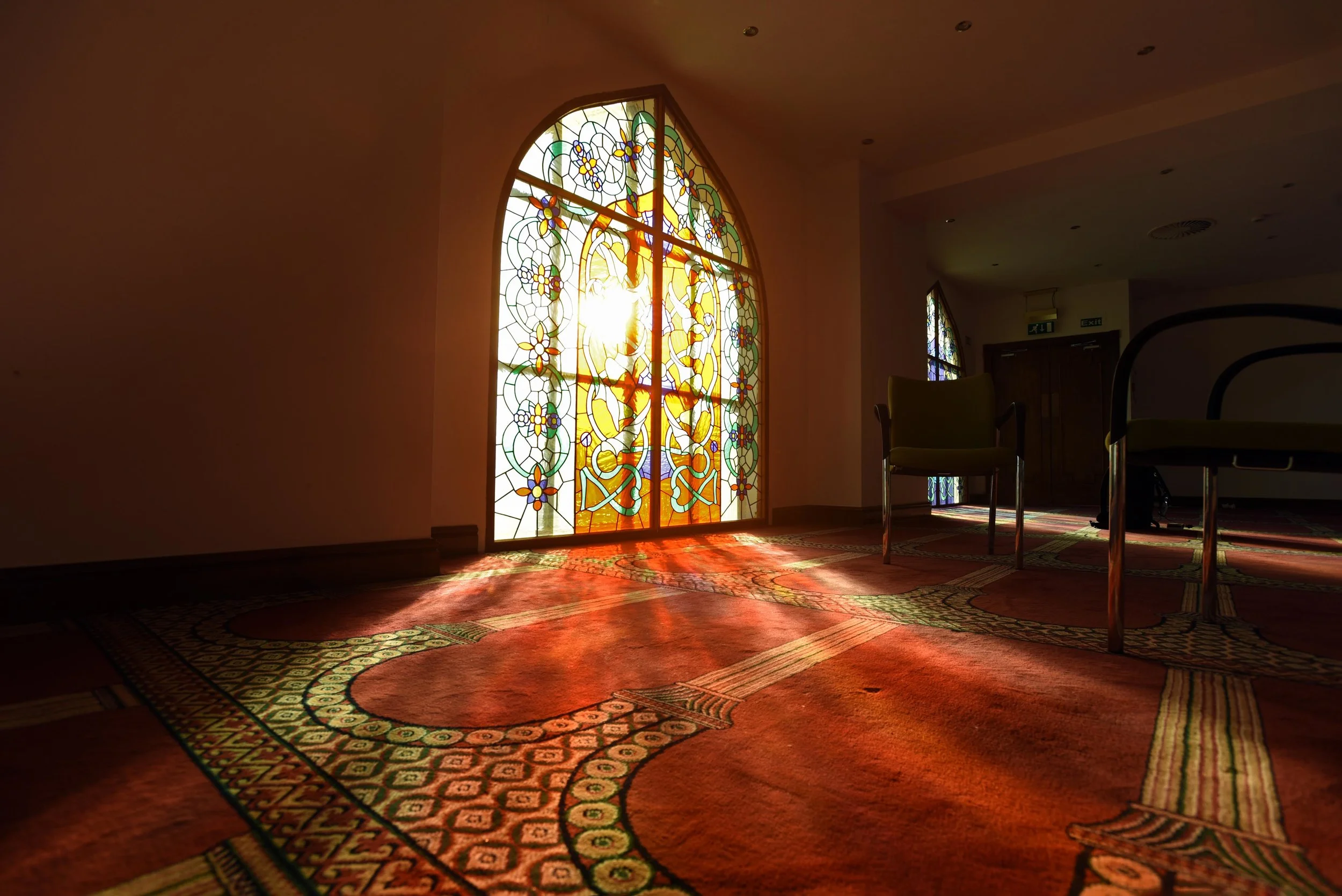 Stained glass window inside Bradford Central Mosque featuring intricate Islamic geometric patterns and vibrant colours, reflecting spiritual and architectural beauty.